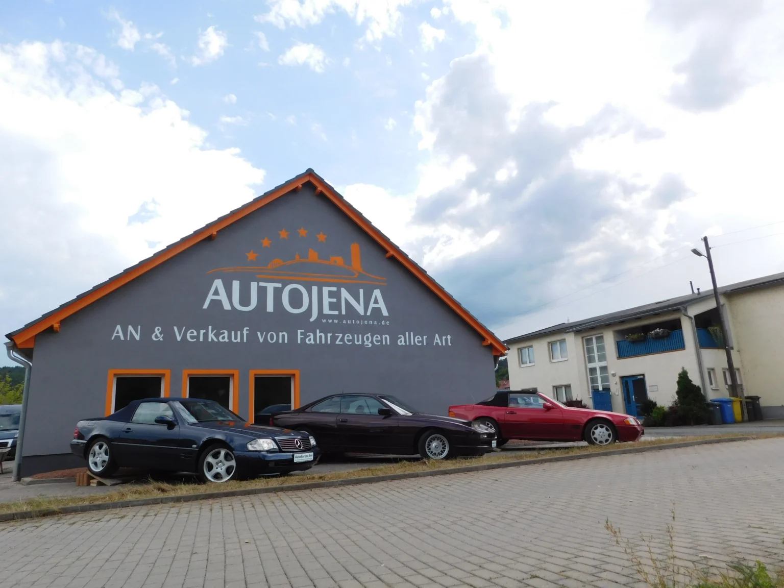 Autohaus AutoJena in Jena mit Gebrauchtwagen vor dem Gebäude