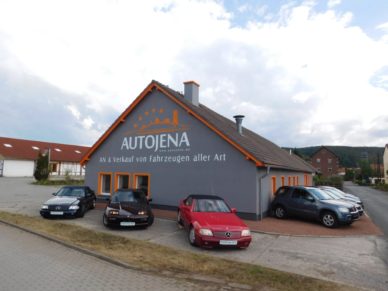 Autohaus AutoJena in Jena mit Gebrauchtwagen vor dem Gebäude